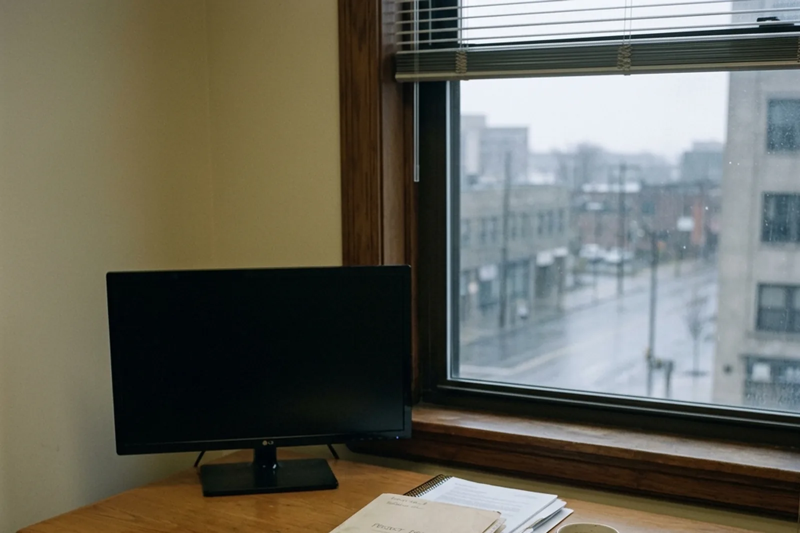 An empty office desk under window light with a notebook.